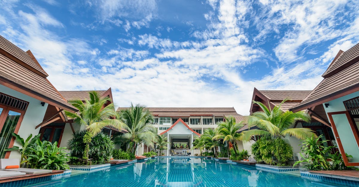 Spacious swimming pool surrounded by tropical villas under a bright blue sky, perfect for relaxation.