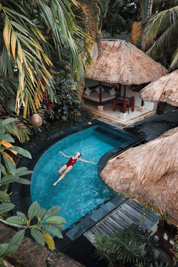 A woman enjoying leisure time floating in a tropical resort pool surrounded by lush greenery.